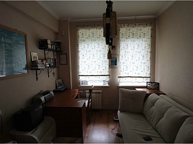 черные открытые полки с книгами над компьтерным столом с принтерем у окна с пестрыми гардинами в спальне  семейной трехкомнатной квартиры сталинского двора