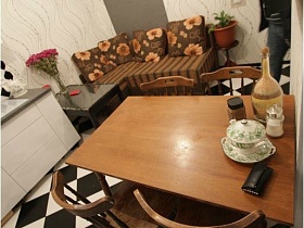 черный журнальный столик с цветами в вазе у полосатого углового дивана в кухне квартиры с выходом на крышу магазина