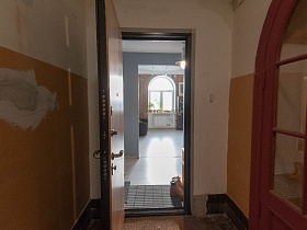 открытая дверь в современную квартиру сталинского дома из коридора, требующего ремонта