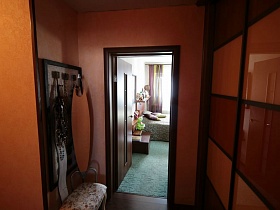 настенная вешалка с мягким цветным пуфиком у входной двери в спальную комнату квартиры оператора