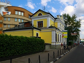 зеленая изгородь красивого желтого двухэтажного особняка в Москве