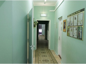 стенд с фотографиями на нежно голубой стене длинного коридора с дорожкой в детском саду