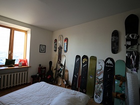 коллекция разнообразных сноудбордов на стене и у белой стены комнаты с современным ремонтом