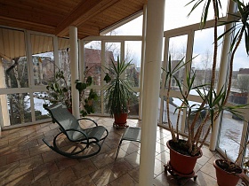 кресо качалка в центре стеклянного зимнего сада