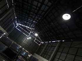единичные светильники под сводами треуголной крыши просторного металлического ангара на лофт территории бизнес-центра