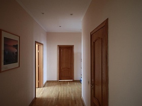 картина в рамке на стене светлого коридора и коричневым линолеумом на полу простой большой квартиры в Марьино