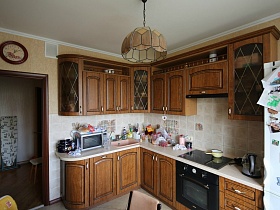 коричневая кухня и коричневая люстра в светлой комнате двухкомнатной квартиры