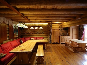 подвесная модульная система с прозрачными абажурами на деревянном потолке в зоне отдыха с красным угловым диваном у деревянных столов
