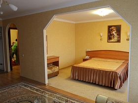 картина и два бра над большой кроватью в спальной комнате гостиничного номера