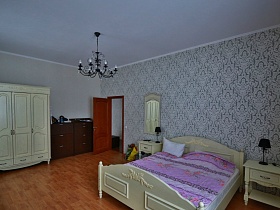 белый шкаф для одежды и коричневые комоды за открытой дверью в светлую спальню современного кирпичного дома
