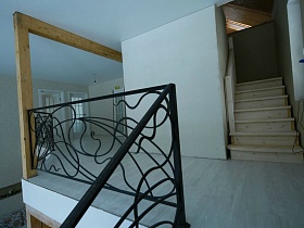 лестничная площадка с фигурными перилами над гостиной и выходом на мансарду по деревянной невысокой лестнице недостроенного элитного дома