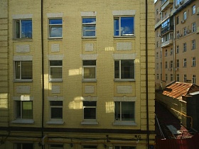 вид на окна жилых квартир соседнего желтого многоэтажного дома из окна скандинавской квартиры