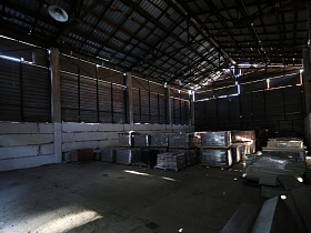 бетонные блоки стен в сочетании с металлическим ограждением высокого ангара  с треугольной крышей на металлических опорах лофт территории бизнес-центра