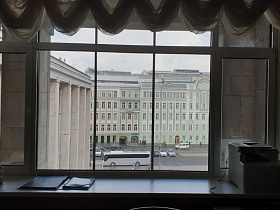 белый пятиэтажный дом напротив и дом с высокими колоннами рядом из окна приемной с белым ламбрекеном, ксероксом и папкой на широком подоконнике при кабинете КГБ СССР