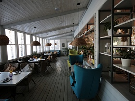 плетенные абажуры подвесных светильников над сервированными столиками различных форм по другую сторону открытого стеллажа с деревянными полками белого ресторана