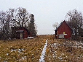 деревянные хозяйственные постройки на большом участке с засохшей травой и тропинкой под снегом