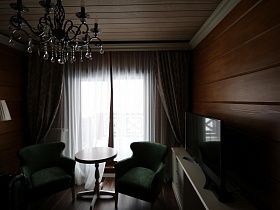 бежевый торшер и люстра, стилизованная под свечи в гостиной современного съемного коттеджа