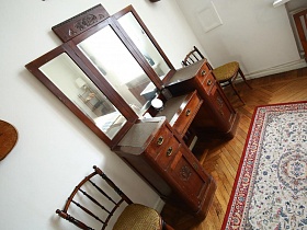 два стула рядом с деревянным трюмо с зеркалами в спальне