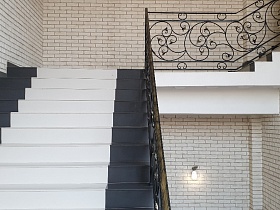 белые с черным ступени лестницы с черными перилами в стильном современном подъезде