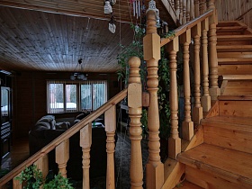резные перила деревянной лестницы на второй этаж современной уютной загородной дачи