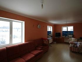 белый потолок и яркие стены просторной комнаты с угловыми диванами, телевизором на столике дома с частичным недостроем для съемок кино