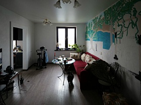 высокий комнатный цветок в углу гостиной у небольшого окна с деревянной рамой в простой семейной разрисованной квартире