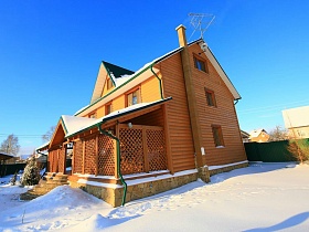 снежный двор с красивым деревянным домом с крытой террасой