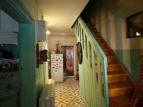вид на ванную комнату с плиткой на стенах и деревянные ступени лестницы на второй этаж избы в деревне