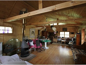 камин, стулья, кресло-качалка, круглый зеленый столик в комнате деревянного домика на дачном участке