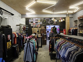 Магазин молодежной одежды, велосипед на стене, лофт стены белого цвета