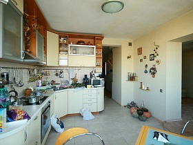 коричневый верх и белый низ мебели с необходимыми кухонными предметами в современной трехкомнатной квартире геолога в многоэтажном доме