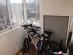 два взрослых велосипеда у стен большого светлого застекленного балкона двухкомнатной квартиры на 6 этаже