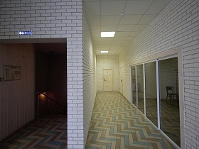 переход с пиццерии по лестнице с перилами в светлый коридор с большими стеклянными дверьми Лофт Бара