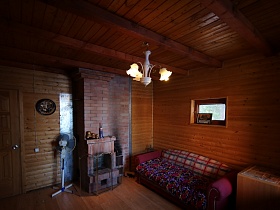 красный мягкий диван, комод, вентилятор в комнате с камином оригинального загородного дома