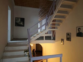 фотографии под стеклом на стене лестницы с перилами на второй этаж гостевого кирпичного дома с придорожным кафе