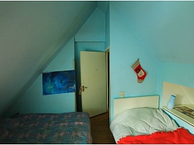 две кровати на полу голубой комнаты с картиной на стене и открытой дверью в мансарде современной дачи