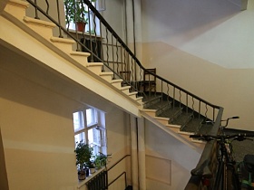 общий вид лестницы с металлическими перилами и деревянными поручнями между этажами в 9 подъезде на Красноказарменной