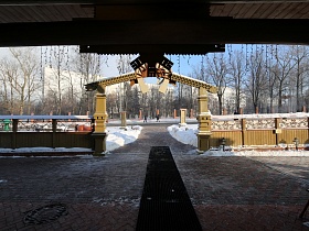 черная дорожка на полу большой территории, выложенной плиткой за забором под крышей с широкими декоративными воротами