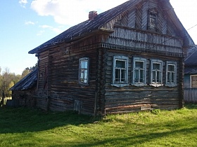 резной декор фасада старого деревянного бревенчатого дома с пристройками на открытом участке в старой деревне