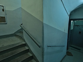 серая квадратная плитка первого этажа подьезда с металлической входной дверью и ступенями лестничной площадки жилого многоэтажного дома эпохи СССР