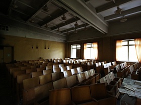 ряды многочисленных деревянных театральных стульев в просторном конференц зале для военных в лофт здании