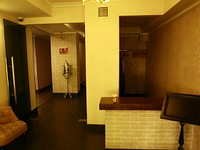 раздевалка за ресепшн,монитор,персиковые мягкие кресла в светлом холле при входе в ресторан на Юге Москвы
