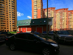 одноэтажное здание с зеленой крышей в современном  дворе высоток