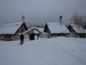 снег на крышах домов с мазанкой на дворике, стилизованном под хутор в коттеджном поселке