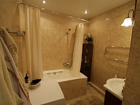 бежевая плитка на стенах, полу и вокруг ванны в ванной комнате трехкомнатной квартиры государственного служащего