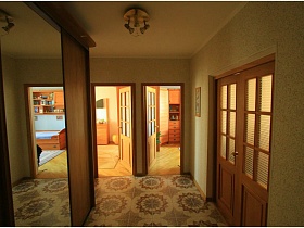 открытые двери в смежные комнаты с общего коридора трехкомнатной квартиры в панельном доме
