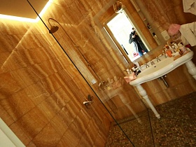 душевая комната за стеклом, зеркало в рамке над белой раковиной на фигурных ножках в ванной комнате девчачьей дизайнерской квартиры с видом на Москву реку