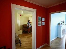 картины в белых рамках на терракотовых стенах прихожей милой женской современной квартиры в новостройке
