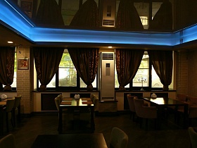 натяжной потолок с неоновой подсветкой по периметру над деревянными столиками в уютном зале хорошего ресторана на Юге Москвы