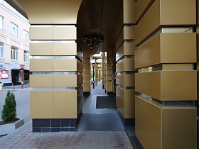 арочные проемы с колонами на центральном входе в современное красивое здание "Казино" золотистого цвета